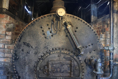 Rustic industrial boiler with intricate metalwork and brick surroundings in Marston, England.